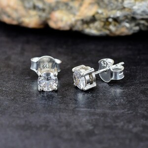 Peut inclure: Une paire de boucles d'oreilles clous en argent avec une pierre de zircone cubique transparente et ronde. Les boucles d'oreilles sont serties dans un sertissage à quatre griffes et ont un fermoir à tige et papillon.