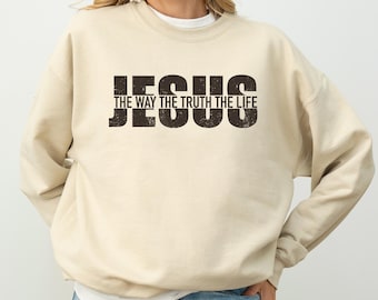 May include: A beige sweatshirt with the text "JESUS THE WAY THE TRUTH THE LIFE" printed in black on the front.