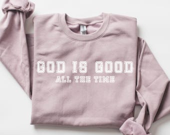 May include: A mauve coloured sweatshirt with the text "GOD IS GOOD ALL THE TIME" in white.