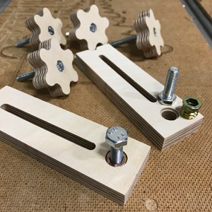 May include: Two wooden blocks with a slot cut out of the center. Each block has a metal bolt and nut attached. There are five wooden knobs with a star-shaped design.