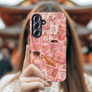 May include: Pink phone case with a coffee and beauty theme. The case features illustrations of coffee cups, croissants, perfume bottles, and text like "But First Coffee" and "Life Happens Coffee Helps".