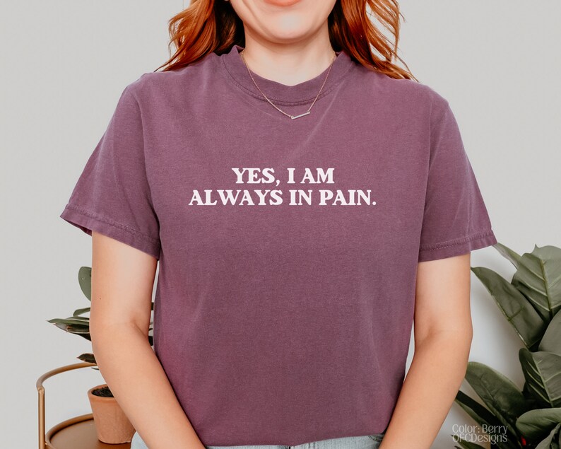 K&ouml;nnte beinhalten: Ein lilafarbenes, bauchfreies T-Shirt mit dem in Wei&szlig; gedruckten Text "YES, I AM ALWAYS IN PAIN."
