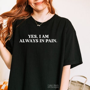 K&ouml;nnte beinhalten: Schwarzes T-Shirt mit wei&szlig;em Text, der "YES, I AM ALWAYS IN PAIN." lautet.