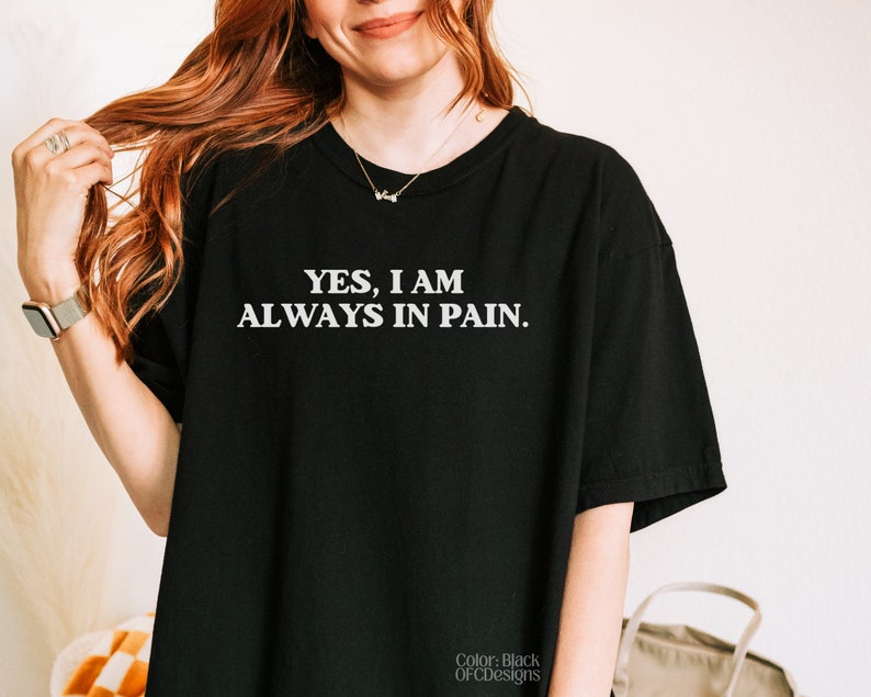 K&ouml;nnte beinhalten: Schwarzes T-Shirt mit wei&szlig;em Text, der "YES, I AM ALWAYS IN PAIN." lautet.