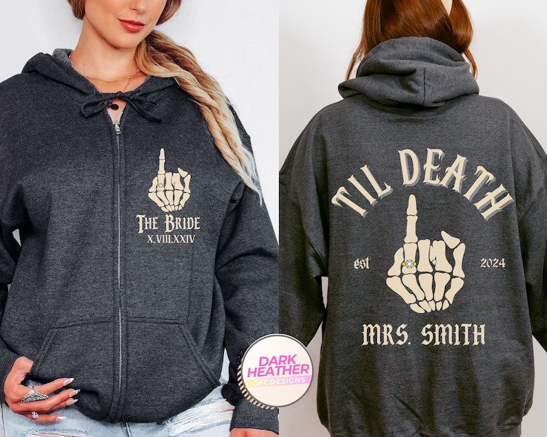 Puede incluir: Sudadera con capucha y cremallera gris oscuro con dise&ntilde;o de mano de esqueleto. En la parte delantera se lee "THE BRIDE" con n&uacute;meros romanos. La parte trasera dice "TIL DEATH" con "MRS. SMITH" y el a&ntilde;o 2024. Ropa tem&aacute;tica de boda.