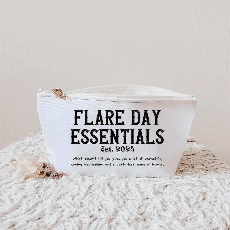 Pode incluir: Bolsa de lona branca com z&iacute;per com o texto "FLARE DAY ESSENTIALS Est. 2024" em preto. Abaixo do texto h&aacute; uma cita&ccedil;&atilde;o. A bolsa est&aacute; sobre uma superf&iacute;cie branca texturizada.