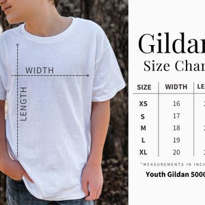 May include: A white t-shirt with a size chart for Youth Gildan 5000B shirts. The chart shows sizes XS to XL with width and length measurements in inches. The shirt is being modeled.