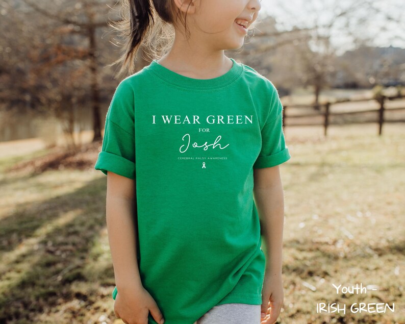 May include: A youth-sized Irish green t-shirt with the text "I WEAR GREEN for Josh" in white. The shirt also features a green ribbon graphic and the words "Cerebral Palsy Awareness".
