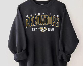 May include: Black sweatshirt with a yellow and blue Nashville Predators logo and the text "Nashville Predators Est. 1998".