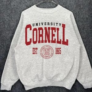 May include: Gray sweatshirt with a red Cornell University logo and the text "University Cornell Est 1865".