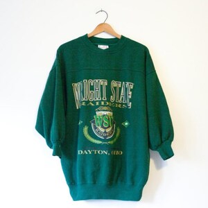 May include: Green sweatshirt with a vintage Wright State Raiders logo and the text "Wright State Raiders Dayton, Ohio".