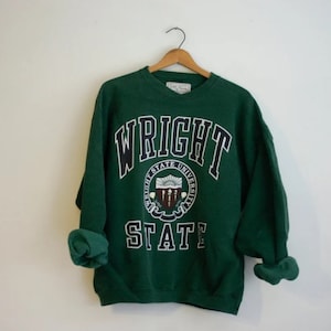 May include: Green sweatshirt with the text "WRIGHT STATE" in black and white lettering. The sweatshirt features a circular logo with the words "Wright State University" and a crest.