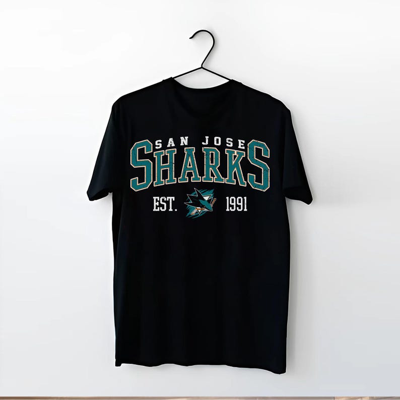May include: Black t-shirt with a white graphic of the San Jose Sharks logo. The logo includes the team name "San Jose Sharks" and the text "Est. 1991".