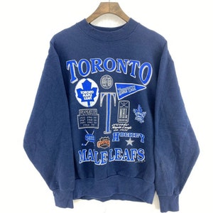 May include: A navy blue sweatshirt with a vintage Toronto Maple Leafs design. The sweatshirt features the team's logo, a hockey stick, and the words "Toronto Maple Leafs" and "Hockey".