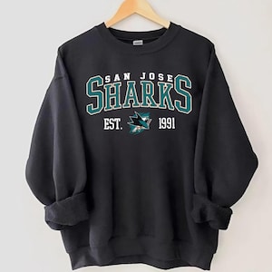 May include: Black sweatshirt with a white and green San Jose Sharks logo and the text "San Jose Sharks Est. 1991".