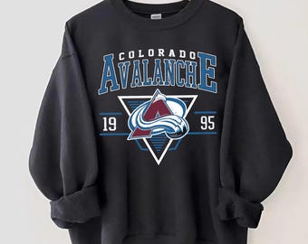 May include: Black sweatshirt with a white triangle and the text "COLORADO AVALANCHE" in blue and white. The triangle contains a blue and white hockey team logo with the numbers "19" and "95" on either side.