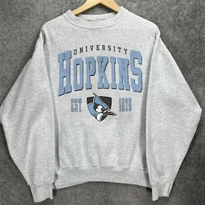 May include: Gray sweatshirt with the text "UNIVERSITY HOPKINS EST 1876" and a blue bird logo.