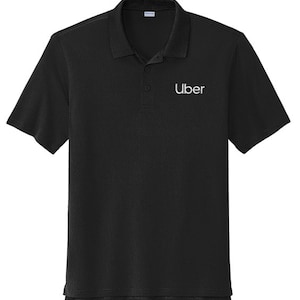 May include: Black polo shirt with short sleeves and a collared neckline. The word "Uber" is embroidered in white on the chest. The shirt has a textured pattern.