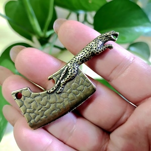 Può includere: Un portachiavi in ​​ottone con un design dettagliato di un leopardo che salta. Il portachiavi include anche un apribottiglie.