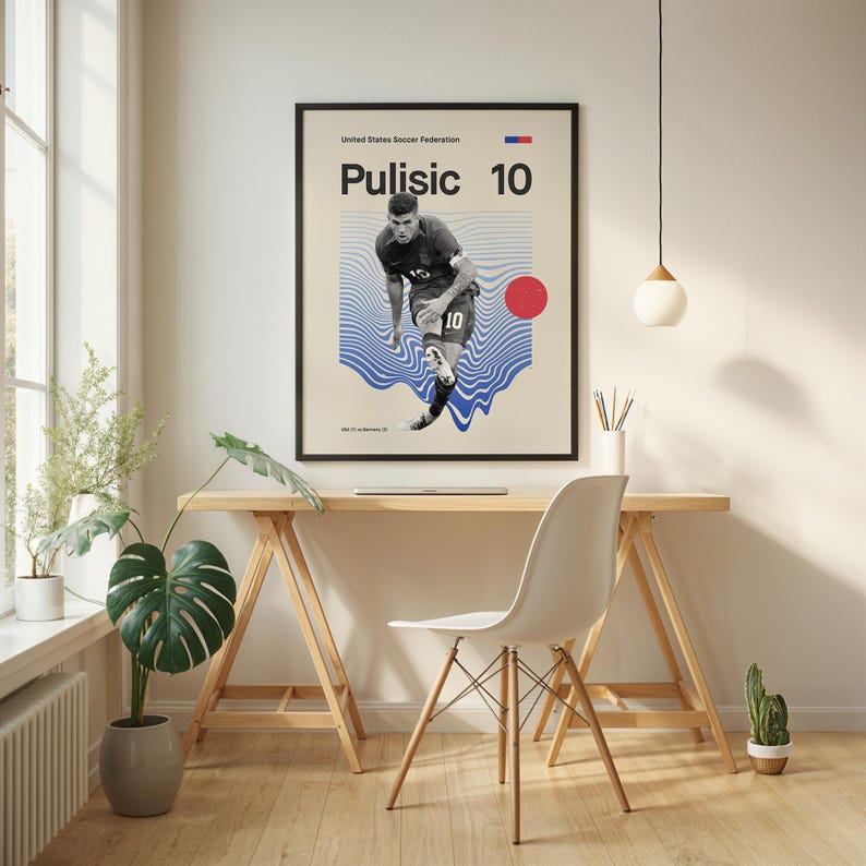 Pu&ograve; includere: Un poster incorniciato con il calciatore Pulisic con il numero 10. Il poster ha uno sfondo beige con linee blu a forma di onda e un cerchio rosso. Il testo "Pulisic 10" &egrave; visualizzato in modo prominente. Il poster &egrave; esposto sopra una scrivania di legno.