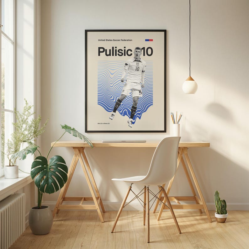 Pu&ograve; includere: Un poster incorniciato con Christian Pulisic in uniforme da calcio bianca con il numero 10. Il poster ha una cornice nera ed &egrave; esposto sopra una scrivania in legno. Lo sfondo presenta motivi a onde blu.