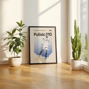 Pu&ograve; includere: Un poster incorniciato con il calciatore Pulisic con il numero 10. Il poster ha uno sfondo beige con grafica a onde blu. Il testo "United States Soccer Federation" &egrave; in alto. Il poster &egrave; appoggiato a un muro.