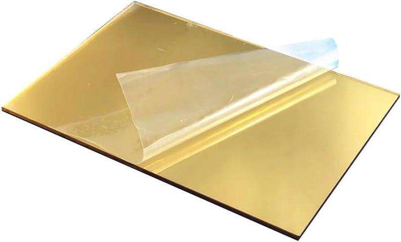 May include: A gold-coloured acrylic sheet with a protective film partially peeled away. The sheet has a reflective, mirror-like surface. The protective film is transparent with a blue tint. The sheet is rectangular.