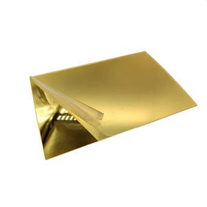 May include: A gold-coloured, rectangular sheet with a corner folded up, revealing a reflective interior. A clear adhesive strip is visible along the folded edge. The sheet has a shiny, metallic appearance.
