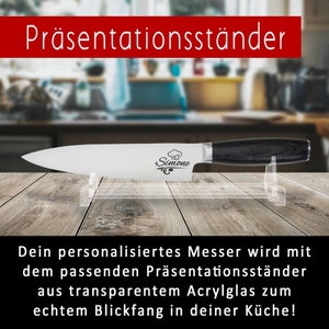 Ein personalisiertes Küchenmesser steht in einem Messerständer in einer Küche. Auf der Klinge ist eine Lasergravur mit einer Kochmütze und dem Namen Simone