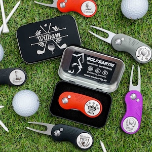 Könnte beinhalten: Ein Set personalisierter Golfball-Marker und Divot-Werkzeuge. Die Marker sind rund und zeigen verschiedene Designs, darunter eine Krone, einen Golfschläger und einen Stern. Die Divot-Werkzeuge sind schwarz, lila und grau und haben einen kleinen, runden Kopf mit einem Golfball-Design. Die Marker und Werkzeuge werden auf einer grünen Grasfläche präsentiert.
