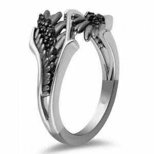 Op de afbeelding: Een zilveren ring met zwarte vleugels. De vleugels zijn gemaakt van kleine zwarte stenen.