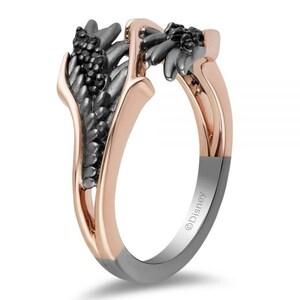 Op de afbeelding: Een ring van ros&eacute;goud en zwart met een vleugelontwerp. De ring is bezet met zwarte stenen en heeft het woord "Disney" gegraveerd op de band.