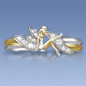 K&ouml;nnte beinhalten: Ein goldener und silberner Ring mit einem Feendesign. Die Fee sitzt auf dem Ring mit ausgebreiteten Fl&uuml;geln. Der Ring ist mit kleinen, klaren Steinen verziert.
