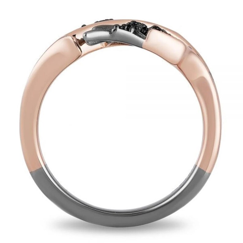 Op de afbeelding: Een ring van ros&eacute;goud en zwart met een gedraaid ontwerp. De ring is gemaakt van twee verschillende metalen, een van ros&eacute;goud en de andere van zwart.