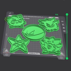 K&ouml;nnte beinhalten: Eine digitale Benutzeroberfl&auml;che zeigt vier hellgr&uuml;ne, 3D-gedruckte Ausstechformen auf einer quadratischen Druckplatte. Die Designs umfassen eine runde Form, eine sternartige Figur und zwei Comic-Figuren. Der Bildschirm zeigt den Text CREALITY.