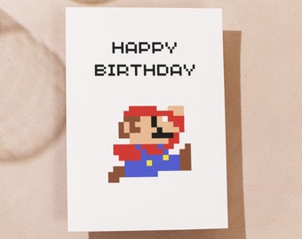 May include: White greeting card with the text "HAPPY BIRTHDAY" in pixelated black letters. Below the text is a pixelated image of Mario in his signature red hat and blue overalls.