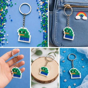 May include: A handmade keychain featuring a pixelated design of a green and blue character. The keychain is attached to a silver metal ring and chain. The character has a white border and is made of small, colorful beads.