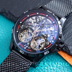 May include: A black and red skeletonised automatic wristwatch with a black mesh metal strap. The watch face features a visible mechanical movement with two exposed gears.