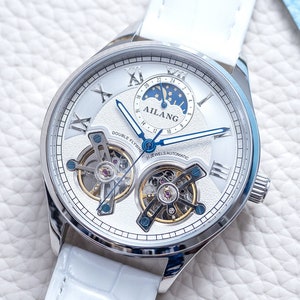 Pu&ograve; includere: Un orologio da polso bianco con quadrante argentato e cinturino in pelle bianca. L'orologio ha un tourbillon a doppia volata e una complicazione di fase lunare. Il quadrante dell'orologio presenta anche il testo "AILANG" e "DOUBLE FLY TOURBILLON 21 JEWELS AUTOMATIC".