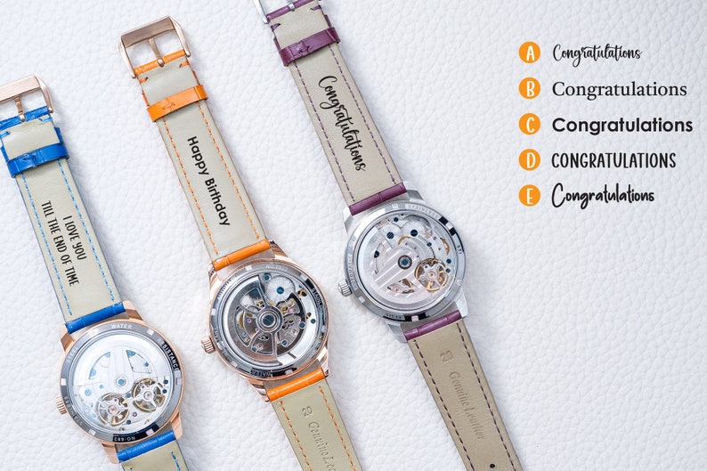 May include: Three wristwatches with different colored leather bands and personalized engravings. The bands are orange, purple, and blue. The engravings read "Happy Birthday", "Congratulations", and "I love you till the end of time".