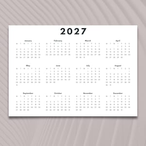 May include: A minimalist 2027 calendar printed on white paper. Each month is displayed with the days of the week and dates. The year "2027" is printed in a bold, sans-serif font at the top.