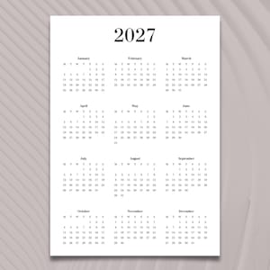 Può includere: Un calendario minimalista del 2027 stampato su carta bianca. Il calendario presenta un design semplice e pulito con l'anno in alto e i layout mensili sottostanti. Ogni mese mostra i giorni della settimana e le date in modo chiaro.