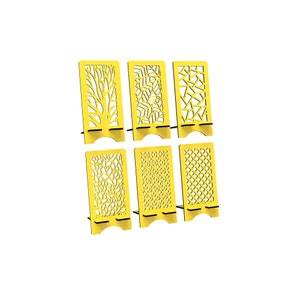 May include: A set of six bright yellow rectangular phone stands, each featuring a unique laser-cut pattern including tree branches, leaves, geometric shapes, and floral motifs. Each stand has a sturdy base with a curved cutout at the bottom.