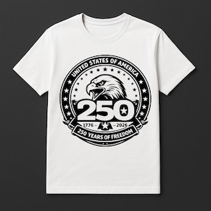 May include: White t-shirt with a black and white graphic celebrating 250 years of freedom. The design includes an eagle, stars, and the text "United States of America" and "250 Years of Freedom". The years 1776-2026 are also displayed.