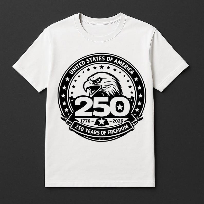 May include: White t-shirt with a black and white graphic celebrating 250 years of freedom. The design includes an eagle, stars, and the text "United States of America" and "250 Years of Freedom". The years 1776-2026 are also displayed.