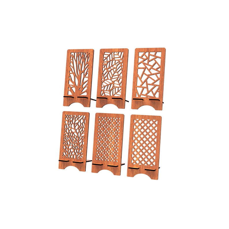 May include: A set of six rectangular wooden phone stands, each featuring a unique laser-cut pattern including tree branches, leaves, geometric shapes, floral motifs, and a lattice grid design, all constructed from a medium-toned brown wood.