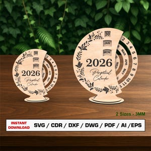 Könnte beinhalten: Zwei ewige Kalender aus hellem Holz. Jeder Kalender zeigt das Jahr 2026, den Monat Januar und den 30. Tag. Das Design umfasst florale Muster und eine kreisförmige Datumsanzeige. Der Text '2 Größen - 3MM' ist ebenfalls sichtbar.