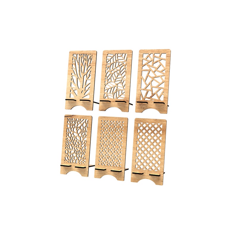 May include: A set of six light brown wooden phone stands, each featuring a unique laser-cut pattern. The designs include tree branches, leaves, geometric shards, organic textures, small circles, and a diamond grid, all with a base support.
