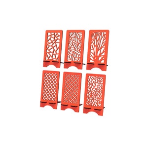 May include: A set of six bright orange rectangular phone stands, each featuring a unique laser-cut pattern. The designs include geometric shapes, leaf motifs, tree branches, a grid pattern, small circular dots, and an intricate floral-like pattern.