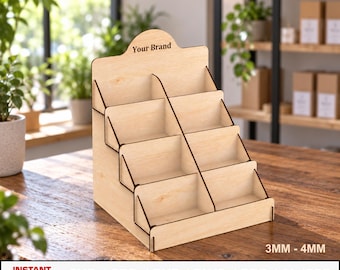Può includere: Un espositore a gradini in legno di colore chiaro con otto scomparti individuali disposti su quattro file. La parte centrale superiore presenta il testo Your Brand. La base include un testo che indica uno spessore di 3MM - 4MM e i formati file SVG, CDR, DXF, DWG, PDF, AI, EPS.